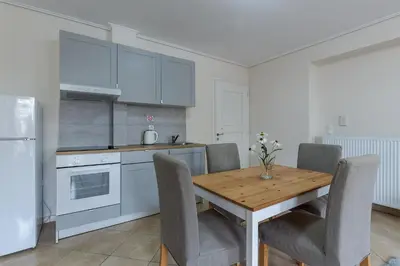 a kitchen with a wooden table with chairs and a refrigerator at UrbanStay in Athens