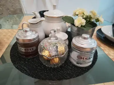 a glass table with three jars and a vase with flowers at The Best Spot in The Center in Athens