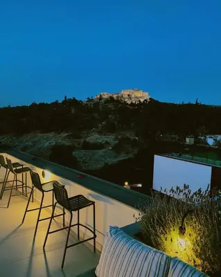 a group of chairs sitting on a balcony at night at Meros - Athenian Residencies in Athens