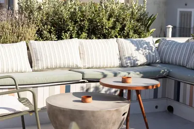 a couch and tables on a balcony with plants at Meros - Athenian Residencies in Athens