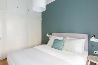 a bedroom with a white bed with a blue wall at Sleek Flat in Central Syntagma by UPSTREET in Athens