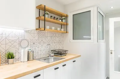 a white kitchen with a sink and a window at Sleek Flat in Central Syntagma by UPSTREET in Athens