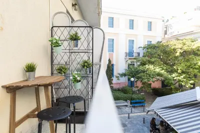 a balcony with a table and two stools and a shelf with plants at Sleek Flat in Central Syntagma by UPSTREET in Athens