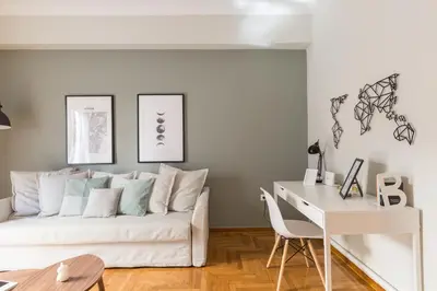 a living room with a white couch and a desk at Sleek Flat in Central Syntagma by UPSTREET in Athens