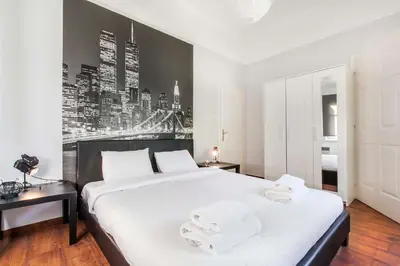 a bedroom with a large bed with white sheets and a wall at Trendy Minimal Flat in posh Athens in Athens