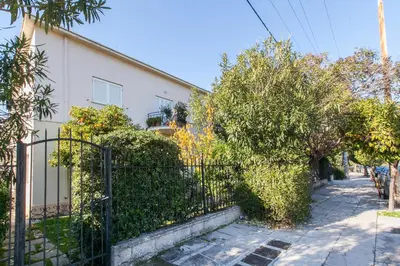 a fence in front of a white building with trees at Trendy Minimal Flat in posh Athens in Athens