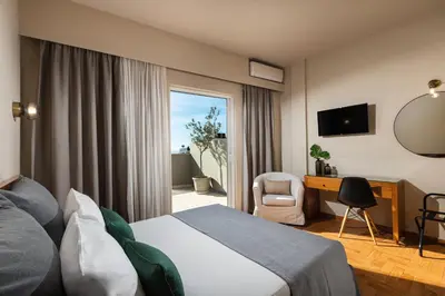 a hotel room with a bed and a desk and a window at Hotel Delfini in Piraeus