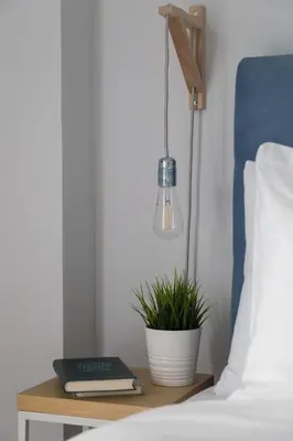 a bedside table with a lamp and a plant on it at Modern Flat next to the USA Embassy by UPSTREET in Athens