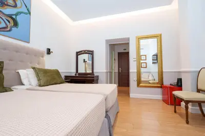 a white bedroom with two beds and a mirror at Acropolis Ami Boutique Hotel in Athens
