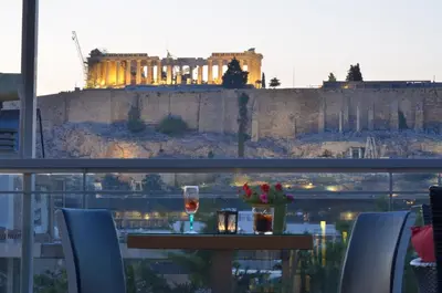 a table with a glass of wine and a view ofhens at Acropolis Ami Boutique Hotel in Athens
