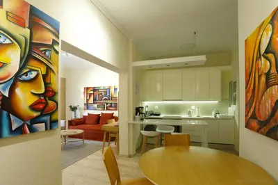 a kitchen and living room with a table and a painting at Charming City Centre Flat Kolonaki in Athens