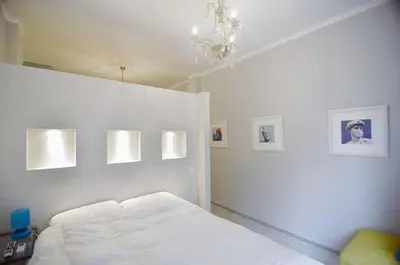 a white bedroom with a bed and a chandelier at Urban Art Experience with Acropolis View in Athens