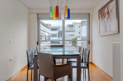 a dining room with a glass table and chairs at Elvita Athens Sea View Maisonette in Athens
