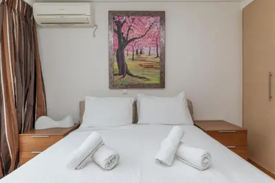 a bedroom with a white bed with three pillows at Elvita Athens Sea View Maisonette in Athens