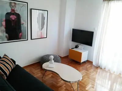 a living room with a couch and a table and a tv at New stylish Kolonaki flat in Athens