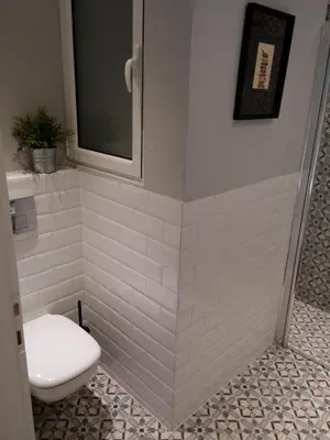 a bathroom with a toilet in a white tiled wall at New stylish Kolonaki flat in Athens
