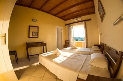 two beds in a room with a window and a piano at Vagia Beach Apartments, Aegina Island in Vaia