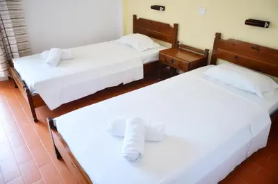 two beds in a hotel room with white sheets at Vagia Beach Apartments, Aegina Island in Vaia