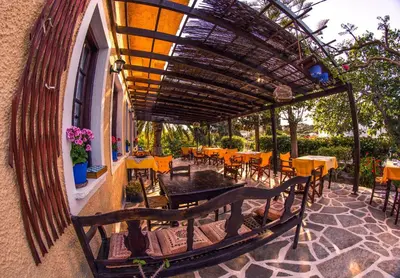 a patio with tables and chairs under a pergola at Vagia Beach Apartments, Aegina Island in Vaia