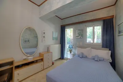 a bedroom with a large bed and a mirror at Villa Sunrise Lagonisi in Lagonissi