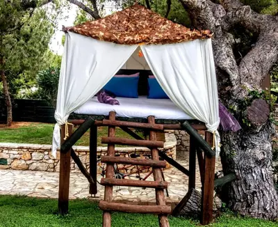 a bed in a tent under a tree at Villa Sunrise Lagonisi in Lagonissi