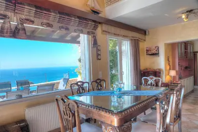 a dining room with a table and a large window at Villa Sunrise Lagonisi in Lagonissi