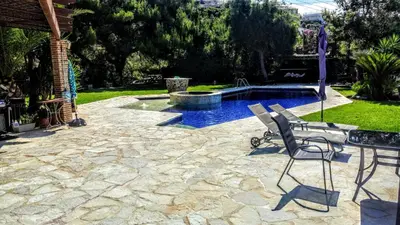 a patio with a table and chairs and a pool at Villa Sunrise Lagonisi in Lagonissi