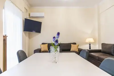 a vase with flowers on a white table in a living room at Victoria Queens Paradise Apartments in Athens