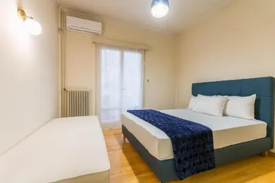a bedroom with a blue and white bed and a window at Victoria Queens Paradise Apartments in Athens