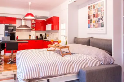 a kitchen with red cabinets and a couch with a table at Martin’s Akropolis loft in Athens