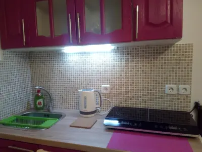 a kitchen counter with red cabinets and a sink at New studio next to metro for 2 people in Athens
