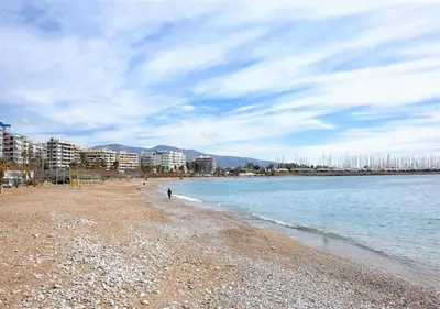 a person walking on a beach next to the water at Athena's Comet in Athens