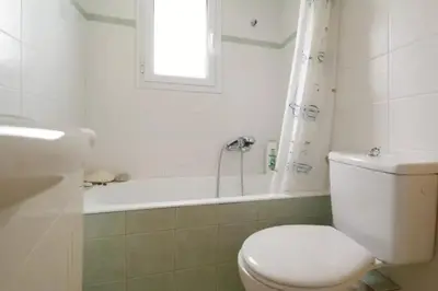 a white bathroom with a toilet and a bath tub at Helen house in Athens