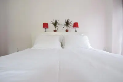 a white bed with two pillows and two plants on it at Acropolis View Apartment in Central Athens! SQ1 in Athens