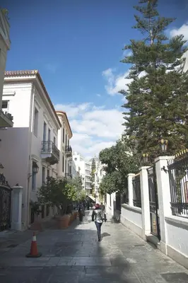 a person walking down a street with an umbrella at Acron of Plaka by YHA in Athens