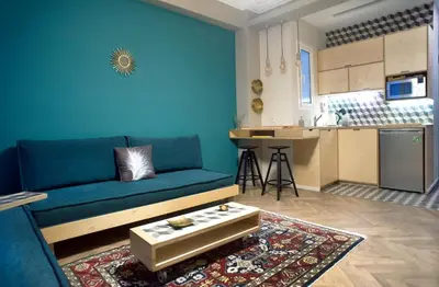 a living room with a blue couch and a kitchen at Acron of Plaka by YHA in Athens