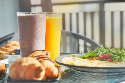 a table with a plate of food and a glass of beer at Mosaikon in Athens