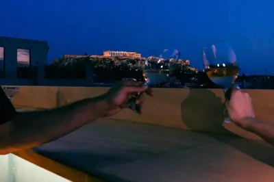 two people holding wine glasses with a view of a city at Mosaikon in Athens