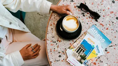 a woman sitting at a table with a cup of coffee at Mosaikon in Athens