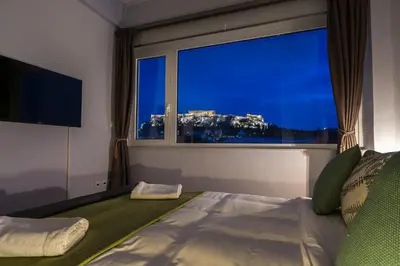 a bedroom with a bed with a large window at Breathtaking View Studio! in Athens