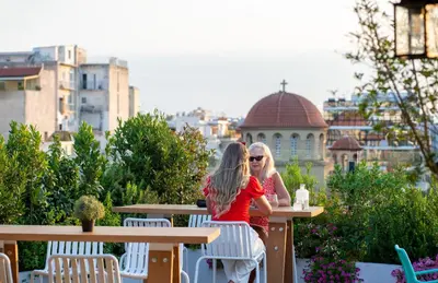 two women sitting at tables on a balcony at B4B Athens Signature Hotel in Athens