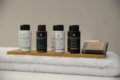 a shelf with four bottles of hair products and towels at B4B Athens Signature Hotel in Athens