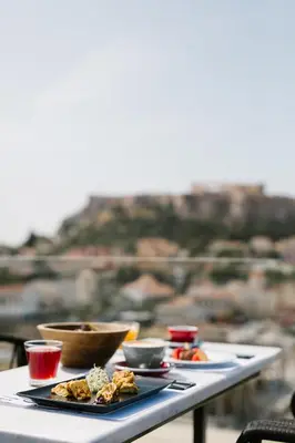 a table with plates of food on it with a view at A for Athens in Athens