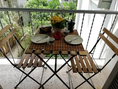 a table on a balcony with plates and flowers on it at Wonderful Apartment in central Athens in Athens