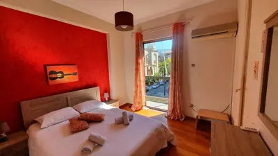 a bedroom with a bed with red walls and a window at Marianas Inn in Athens