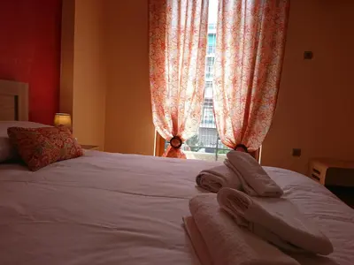 a bedroom with a bed with white sheets and a window at Marianas Inn in Athens