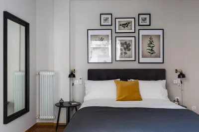 a bedroom with a large bed with framed pictures on the wall at Chic Flat in the Heart of Athens by UPSTREET in Athens