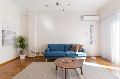 a living room with a blue couch and a table at Chic Flat in the Heart of Athens by UPSTREET in Athens