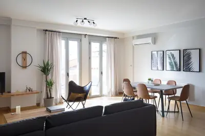 a living room with a couch and a table and chairs at Stylish and Spacious 2BD - Thiseio by UPSTREET in Athens