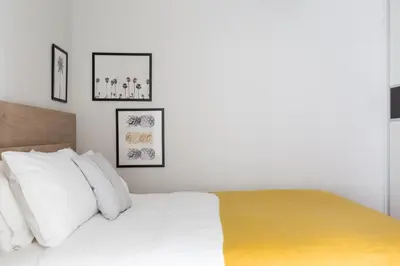 a bedroom with a white bed with four pictures on the wall at Stylish and Spacious 2BD - Thiseio by UPSTREET in Athens